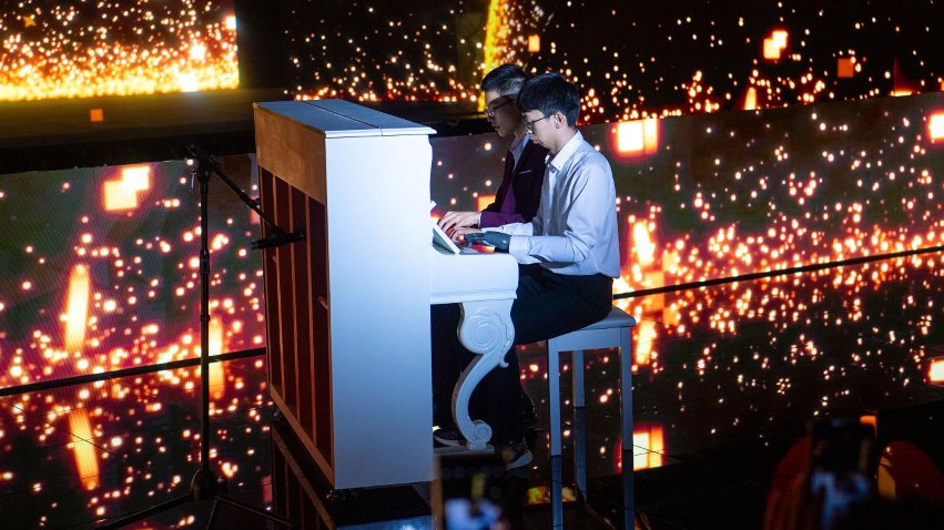 智能仿生手使用者古月與少年鋼琴家舒海峰合奏。主辦方供圖